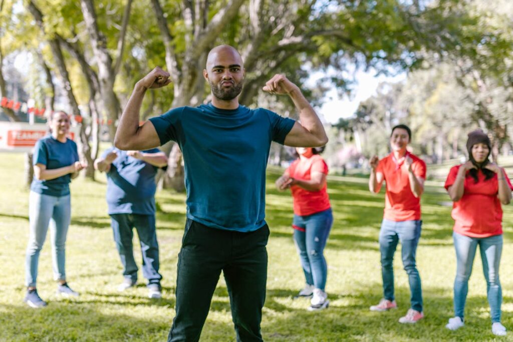 A group of people in navy and red shirts pose for the camera. One fellow in the foreground makes a silly face while flexing.